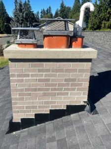 freshly rebuilt chimney with new flashing, poured concrete crown and stainless steel chimney caps