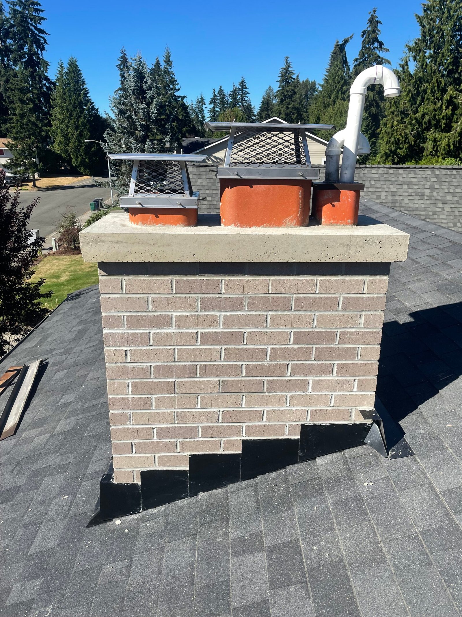 freshly rebuilt chimney with new flashing, poured concrete crown and stainless steel chimney caps 
